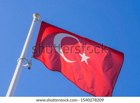 Turkish flag waving in the wind against a blue sky.