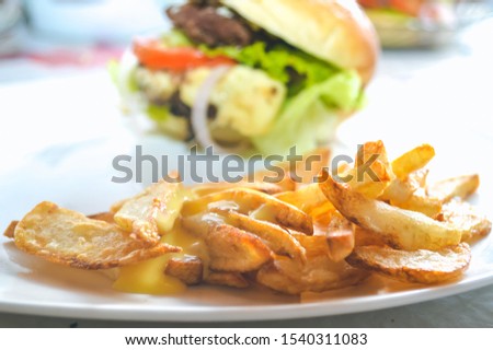 Good fresh crispy homemade fries with homemade hamburger in the background.