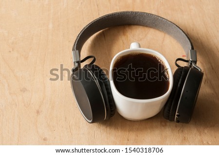 Smartphone, headphones and coffee cup on rustic wooden table. Top view 