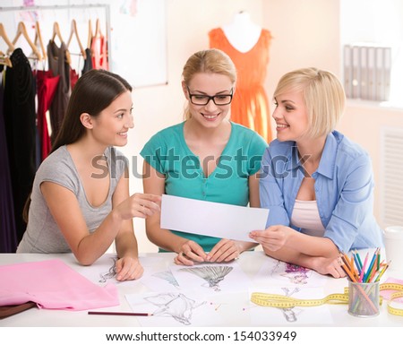 Fashion designers at work. Three cheerful young women working at fashion design studio
