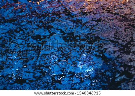 Wet surface with reflections of multi-colored lights in the night. Abstract dark blue background with neon grales in rainy weather