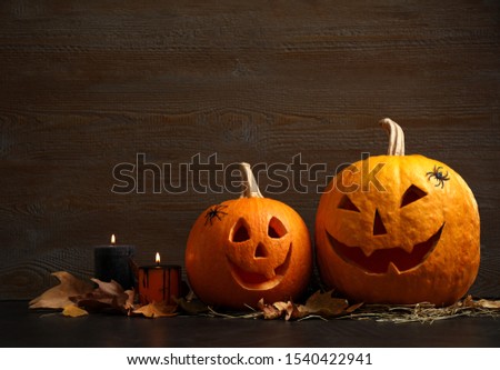 Spooky Jack pumpkin head lanterns on grey table against wooden background, space for text. Halloween decoration