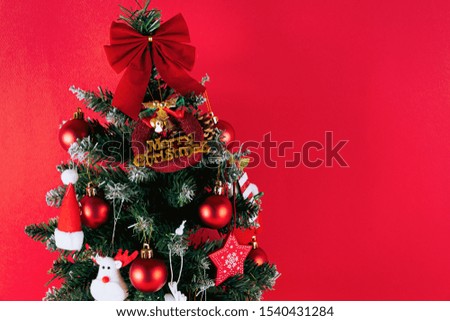This is a picture of a green Christmas tree with a red background and red decorations.Designers can work in an empty area.This is the background image of the Christmas concept.