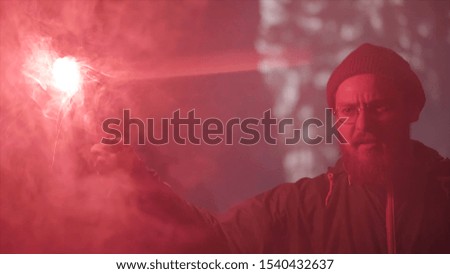 Young man found a narrow hole inside the cave and illuminates the way with red burning signal flare. Stock footage. Absolutely deep darkness around in grotto.