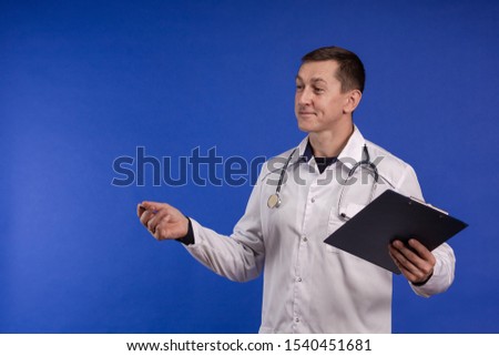 Male doctor in a white coat posing on a blue background