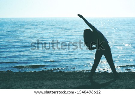 Silhouette of a woman doing sports exercise on the seashore