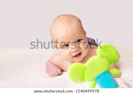 Baby infant playing and smiling with a colorful green toy Royalty-Free Stock Photo #1540499978