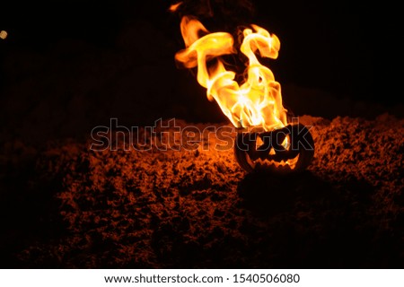 Tongues of flame in a pumpkin. jack-o-lantern on fire on a black background. Halloween symbol on the ground. Trick or treat. Close up.