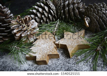 Christmas toys from natural materials with cones and pine branches on a dark background, powdered with snow.  Christmas, New Year.