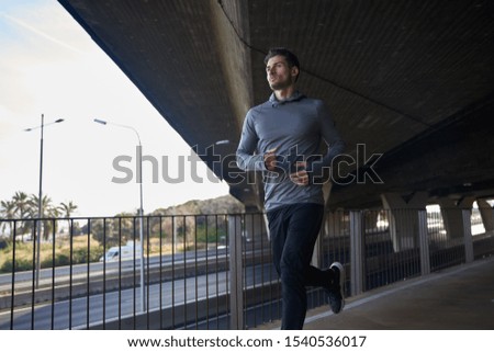 Man runs under bridge over a motor was dressed in athletic running clothes