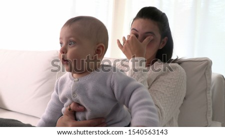 Tired mother with baby infant at home