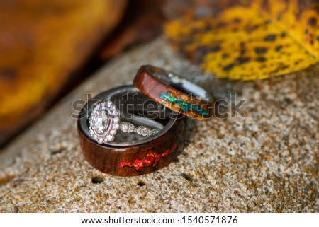 Engagement and wooden fire opal wedding rings in a fall background