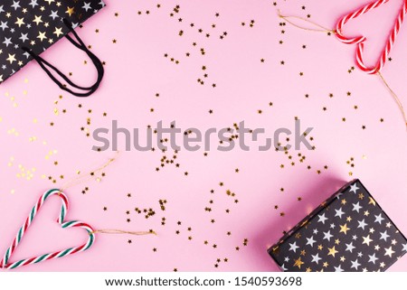 Christmas symbol flat lay frame on pink with golden star confetti. Festive background with gift boxes and bags