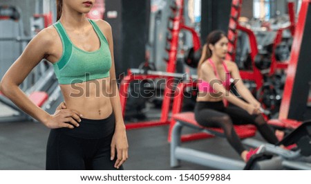 Young Asian women with perfect abdomen muscles in the modern gym and Hard training. Dieting results, fitness, active lifestyle concept