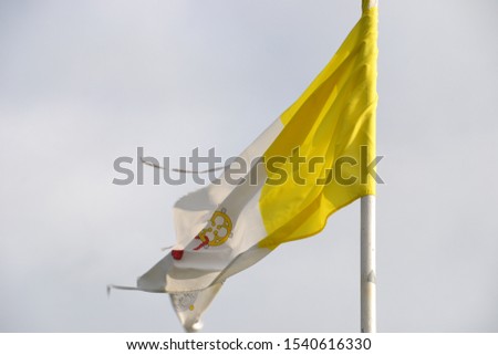 old tattered papal flag blowing on a story day