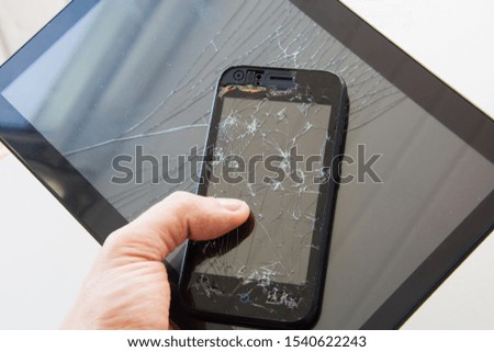 A man holds a broken smartphone and a broken tablet. Rejection of modern technology and gadgets.