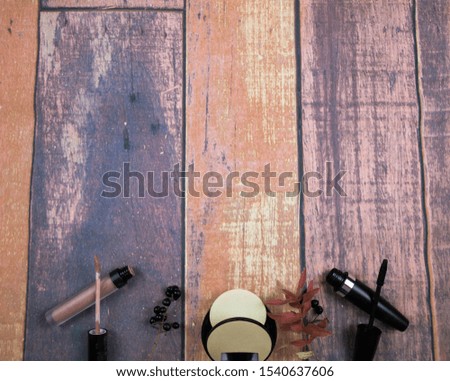 Various makeup products on wooden background with autumn decoration