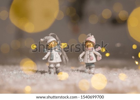 Decorative Christmas-themed figurines. Statuette boy and girl in knitted hats and scarves. Christmas tree decoration. Festive decor, warm bokeh lights