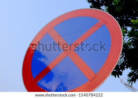 A red "X" shaped traffic sign that prohibits parking on the roadside. Violation of the rules will be warned and punished by the police.