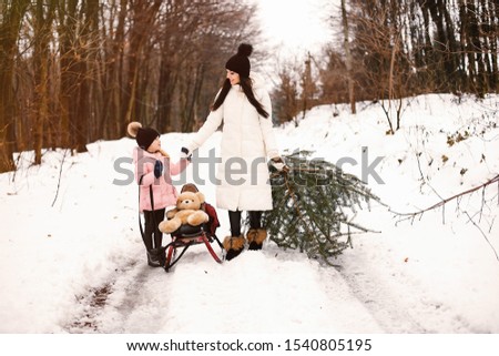 Family have fun in a winter park. Stylish mother in a white jacket. Little girl in a winter clothes.