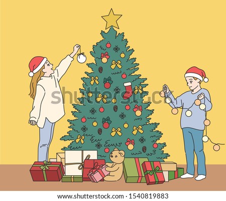 Cute boy and girl are decorating the Christmas tree. hand drawn style vector design illustrations. 