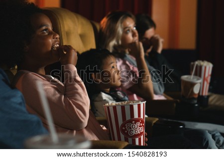 diversity people children and young people having fun watching movie and eating popcorn in cinema theater
