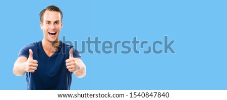 Happy excited of man in blue smart casual clothing, showing two thumb up hand gesture, over blue background. Copy space for some ad sign text or slogan.