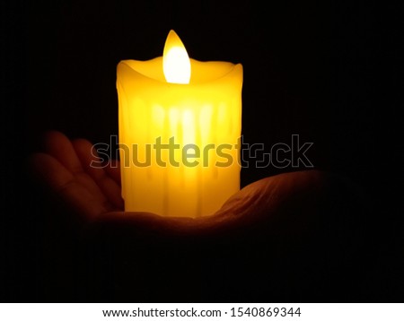 One hand holding the candle in dark