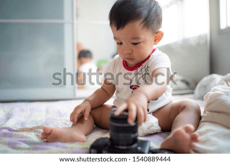 Adorable baby boy playing with camera in cozy room