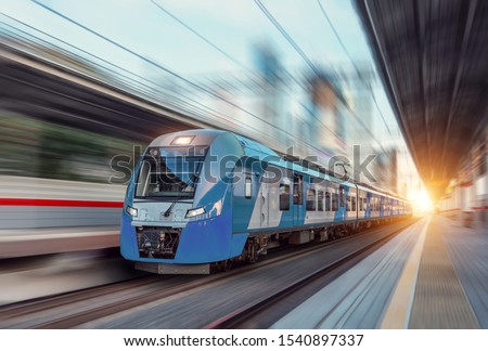 Electric passenger train drives at high speed among urban landscape Royalty-Free Stock Photo #1540897337
