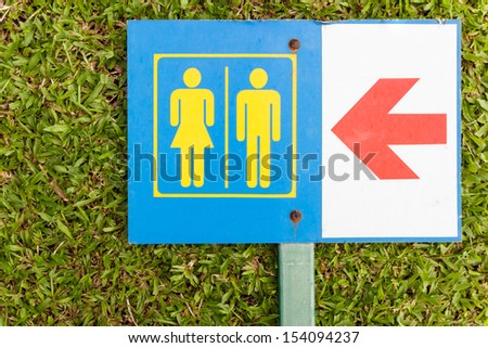 The Guide post arrow to restroom for men and women on grass