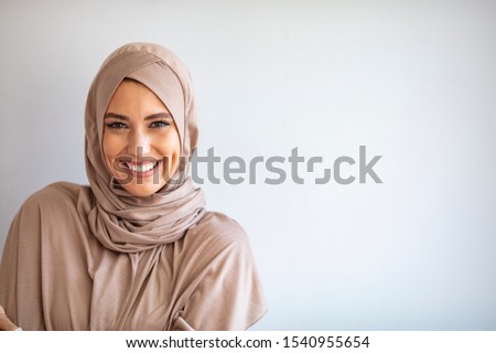 Modern, Stylish and Happy Muslim Woman Wearing a Headscarf. Arab saudi emirates woman covered with beige scarf. "Welcome" Face. One women smile with white background  Royalty-Free Stock Photo #1540955654