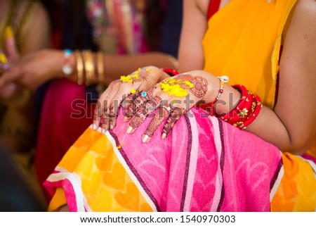 Closeup of Indian bridal haldi and mehndi henna hands, pasting turmeric paste for haldi Ceremony.