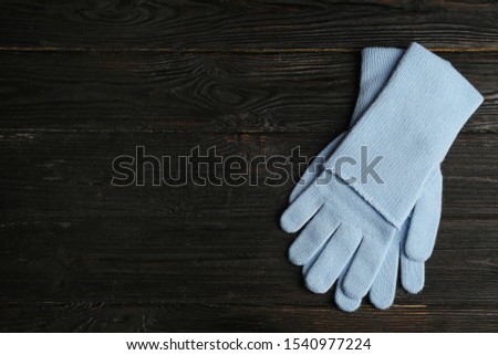 Stylish blue gloves on dark wooden background, top view with space for text. Autumn clothes