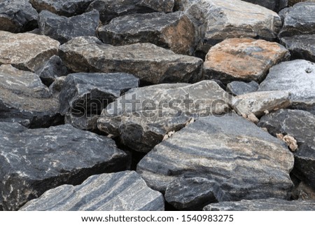 natural close up filled frame background wallpaper shot of large black grey granite rock stones on the beach forming beautiful patterns and shapes