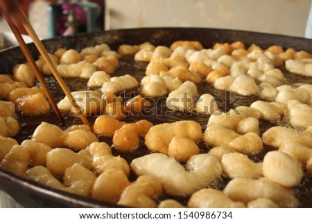 Frying deep fried dough sticks in pan of hot cooking oil. Chef cooking and prepare white raw flour on table beside. The street food in Thailand. Chinese and Thai Style. Asian food concept.Select focus Royalty-Free Stock Photo #1540986734