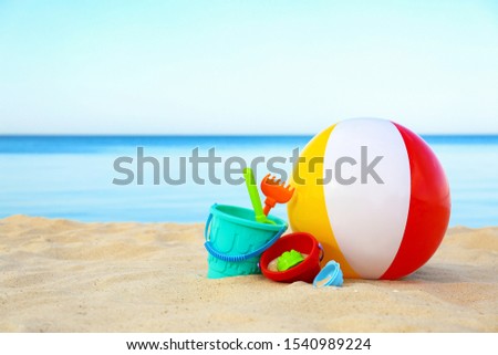 Set of plastic beach toys and colorful ball on sand near sea. Space for text Royalty-Free Stock Photo #1540989224