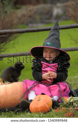 Little witch with a kitten and pumpkins