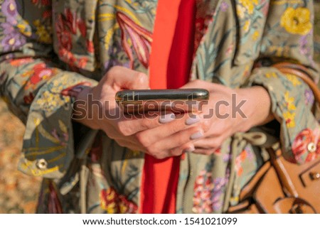 Cropped image of a close-up woman's hand holding a cellphone for navigation data during her autumn trip, a woman using her smartphone to view interesting places on a map