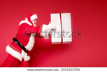 Photo of real Santa Claus with a huge red gift box. Merry Christmas and Happy New Year concept.A lot of copy space.