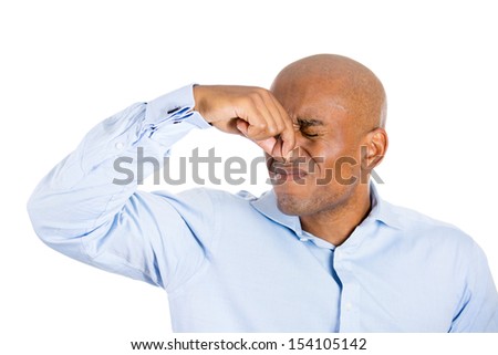 Closeup portrait of handsome guy closing nose because something stinks, isolated on white background with copy space