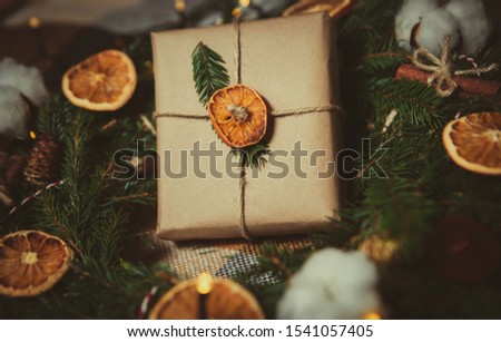 Handmade presents for Happy New Year 2019 celebration.Christmas Eve gift box in green fir tree branches decorated with garland and dry oranges.Beautiful hand made gifts for winter holidays in close up