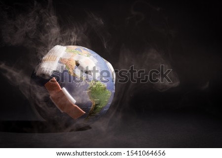 White smoke cover around the globe (earth) full of bandages, showing the world is affected from pollution, greenhouse gases in black and dark background. Climate change, Earth day, Net zero 2050. Royalty-Free Stock Photo #1541064656