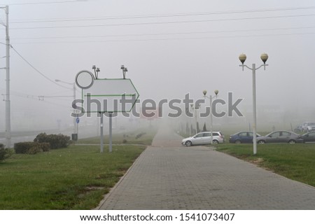 Photo of the autumn city in the fog. Cloudy weather, boring mood. Buildings and roads in the fog.