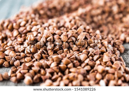 A pile of uncooked buckwheat scattered on old boards. Buckwheat is used for cooking. Close-up.