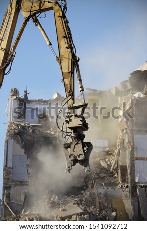 Demolished old soviet union building remains with orange bulldozer