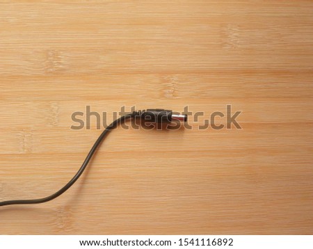 Black color male connector of power plug adapter kept on wooden table