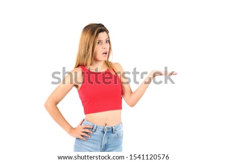 Beautiful surprised young woman doing a hand gesture to one side against a white background