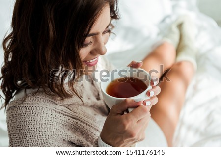 attractive woman in grey sweater holding cup of tea at morning  Royalty-Free Stock Photo #1541176145