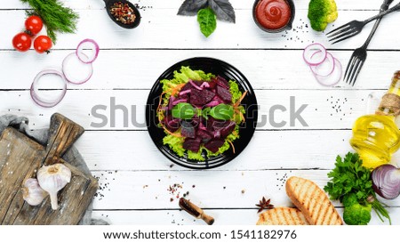 Beet salad with onions in a black plate on a white wooden background. Top view. Free space for your text.